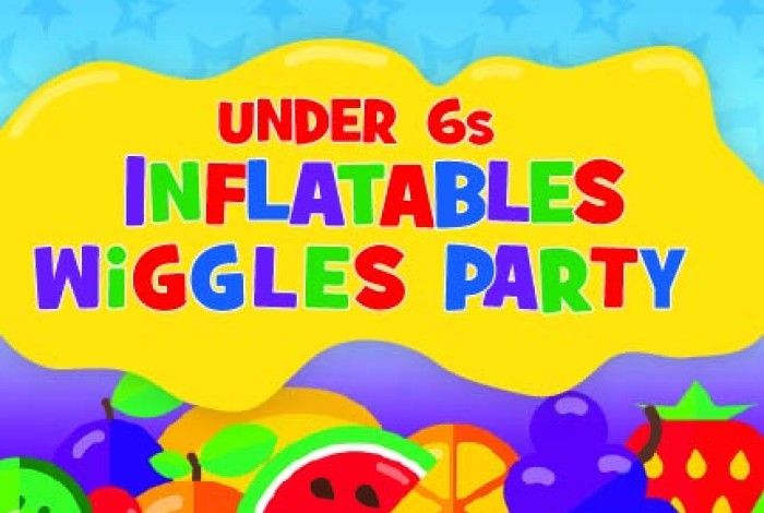 Bright, colourful graphic promoting an “Under 6s Flatables Wiggles Party”. The text appears in large, playful multicoloured letters on a yellow paint-splash shape against a blue patterned background. The bottom of the image features vibrant cartoon fruit illustrations, including watermelon, orange slices, grapes and strawberries